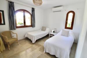 ein Zimmer mit zwei Betten und einem Stuhl und zwei Fenstern in der Unterkunft Beautiful Three-Bedrooms El Rancho Villa in Atamaría