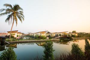 eine Palme, einige Häuser und ein Gewässer in der Unterkunft Bua Tara Resort in Nong Prue
