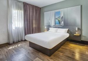 a large bed in a room with a large window at B&B HOTEL Angoulême in Le Gond-Pontouvre