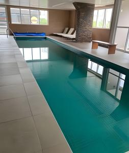 a swimming pool with blue water in a building at 506 Alphaville Link Studio in Aldeia