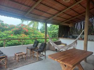 a porch with a hammock and chairs and a table at Hostel X DE CARAIVA in Caraíva