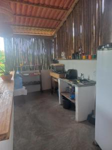 a room with a kitchen with a counter and a refrigerator at Hostel X DE CARAIVA in Caraíva