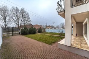a house with a brick driveway next to a fence at Villa cu 4 dormitoare de 3 stele Timiș, perfectă pentru familii sau grupuri in Utvin