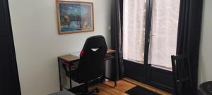 une chaise noire dans une chambre avec un bureau et une fenêtre dans l'établissement Chez Philippe et Agnès Studio, à Vauciennes
