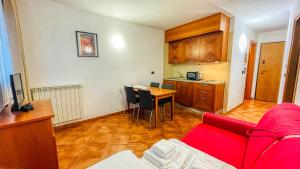 un soggiorno con un divano rosso e una cucina di Appartamento Smith Malvasia - Solo Affitti Brevi a Bardonecchia