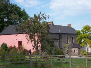 Ein Mann steht vor einem rosa Haus. in der Unterkunft Brynderwen in Llangorse