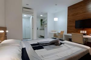 巴西利亚Vision, local nota 10! Academia, sauna e piscinas.的一间卧室配有一张大床、一张桌子和一台电视机。 更多32张照片