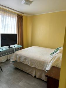 ein Schlafzimmer mit einem Bett und einem Flachbildfernseher in der Unterkunft Casa Condominio la Bahía in Coquimbo