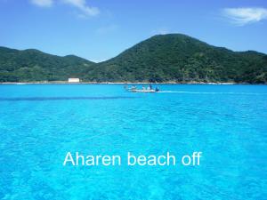 a boat on the water with a beach in the background at Tokashiki Guest House in Tokashiki