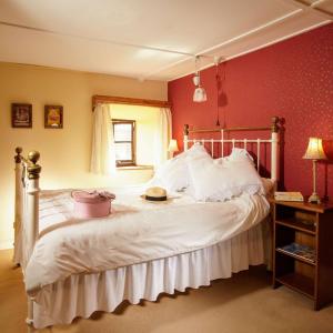 a bedroom with a white bed with a hat on it at Spindle Cottage Holidays in Radstock