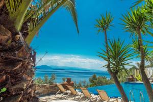 a pool with chairs and palm trees and the ocean at Pounda Paou in Metókhion