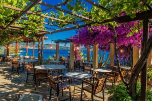 a restaurant with tables and chairs under a pergola with purple flowers at Pounda Paou in Metókhion
