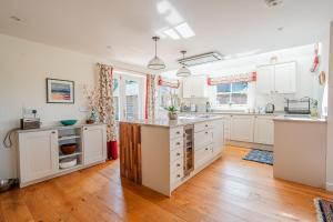 a kitchen with white cabinets and a hardwood floor at Beautiful Cottage in Brockenhurst with Forest View in Brockenhurst
