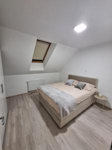 a white bedroom with a bed and a window at Apartman REINA HOME in Prijedor
