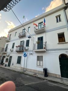 a white building with two flags on top of it at Appartamento Lepanto in Marina di Gioiosa Ionica +27 photos
