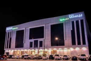 een groot gebouw met auto's geparkeerd op een parkeerplaats bij بيستانا للشقق المخدومة 2 in Riyad