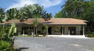 una casa con una palmera delante en Baan Rim Tarn B&B, en Takua Pa
