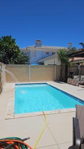 a large blue swimming pool in front of a house at Praia Xangri-lá Atlântida Capão da Canoa Torres in Xangri-lá