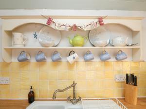 a kitchen with dishes on a shelf above a sink at Trehan in St Ives +19 photos