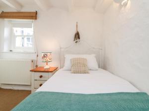 a bedroom with a white bed and a night stand with a lamp at Trehan in St Ives