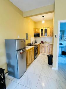 a kitchen with wooden cabinets and a stainless steel refrigerator at Jett Room - Ferdie's Place in Port Antonio
