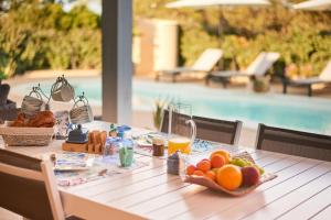 a table with fruit and juice on it with a pool at Villa Corallo in Costa Rei