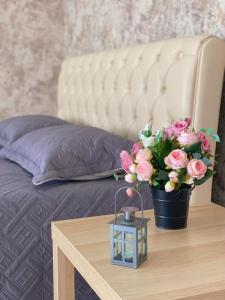 a vase of pink flowers on a table next to a bed at Однокомнатная студия, центр города in Kostanay