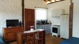 a kitchen with a small table and a refrigerator at Chalés do Caminho - Afeto in Santa Rita do Rio Abaixo