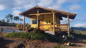 a small yellow house with a wooden roof at Chalés do Caminho - Afeto in Santa Rita do Rio Abaixo