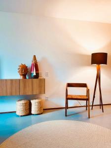 a room with a chair and a table and a lamp at Lindo Apartamento em condomínio de frente para o mar - Villa Naluri B107 in Japaratinga