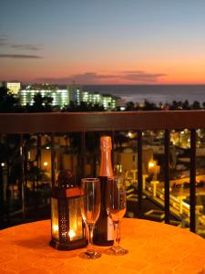 a table with two glasses and a bottle of wine at Blanco&Azul - Ocean View Balcony, Pool and Perfect Location in Playa de las Americas