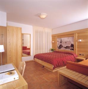 Schlafzimmer mit einem Bett, einem Schreibtisch und einem Tisch in der Unterkunft Hotel Ariston ***S in Madonna di Campiglio