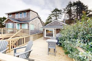 a deck with two chairs and a house at Baerfoot Bungalow in Cannon Beach