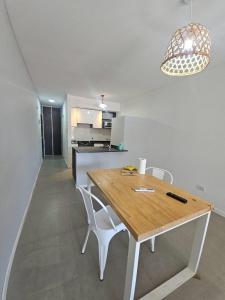 a kitchen with a wooden table and white chairs at Alquiler Temporario Rosario 22 in Rosario