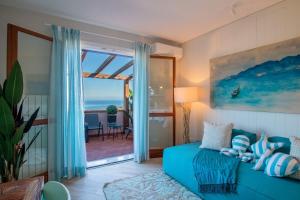 een woonkamer met een blauwe bank en uitzicht op de oceaan bij Pandora Sea View by Solturelba in Capoliveri