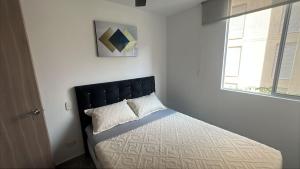 a bedroom with a bed with a black headboard and a window at Lujoso Apto 5 min de Clínica Valle de lili y CC Jardín Plaza, 2207 in Cali