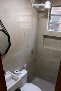 a bathroom with a toilet and a sink and a window at Coral - Praia da Pipa in Pipa