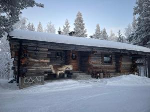 a log cabin with a dog standing outside in the snow at Kelogornitsa - Levikeskus 2 km - ski bus 300 m in Kittilä +78 photos