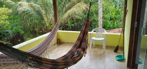a hammock on the balcony of a house with a chair at CHALÉ LUZIMAREs 01 in Ilhéus
