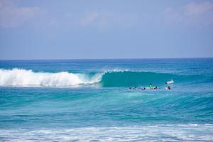 a group of people riding a wave in the ocean at La Curadiña - Encuentro Surf Hotel in Cabarete