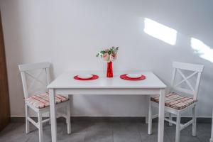 a white table with two chairs and a vase with flowers at Aristomenis House Lentas in Lentas