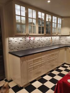 a kitchen with white cabinets and a checkered floor at Modern villa for rent in Lavangen