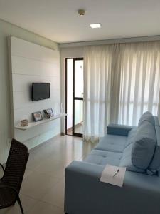 a living room with a blue couch and a tv at Manawa Beach Flats Prime in Porto De Galinhas