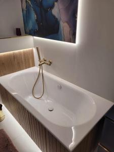a white sink in a bathroom with a painting on the wall at Apartament Cień Wiatru z Widokiem na Jezioro i Netflixem in Charzykowy