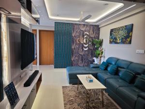 a living room with a blue couch and a tv at Evara - Premium Fully AC - 3BHK Luxury Apartment with Style in Trivandrum