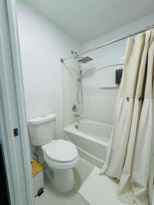 キシミーにあるFamily stay Near Disneyのトイレとシャワー付きの白いバスルーム