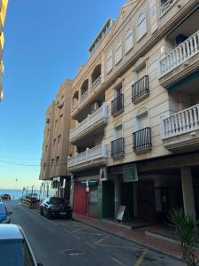 a building with balconies and a car parked on a street at Casa del Sombrero Los Locos beach in Torrevieja