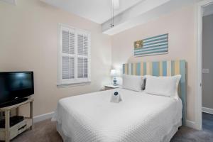 a white bedroom with a bed and a tv at Island Royale 902 in Gulf Shores +28 photos