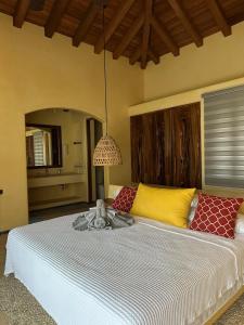 a bedroom with a large bed with yellow and red pillows at Casamar, beach front estate on Troncones Point in Troncones