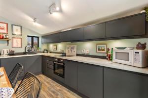 a kitchen with gray cabinets and a white microwave at Foxes Walk - Rural Views Rustic Charm in Templeton